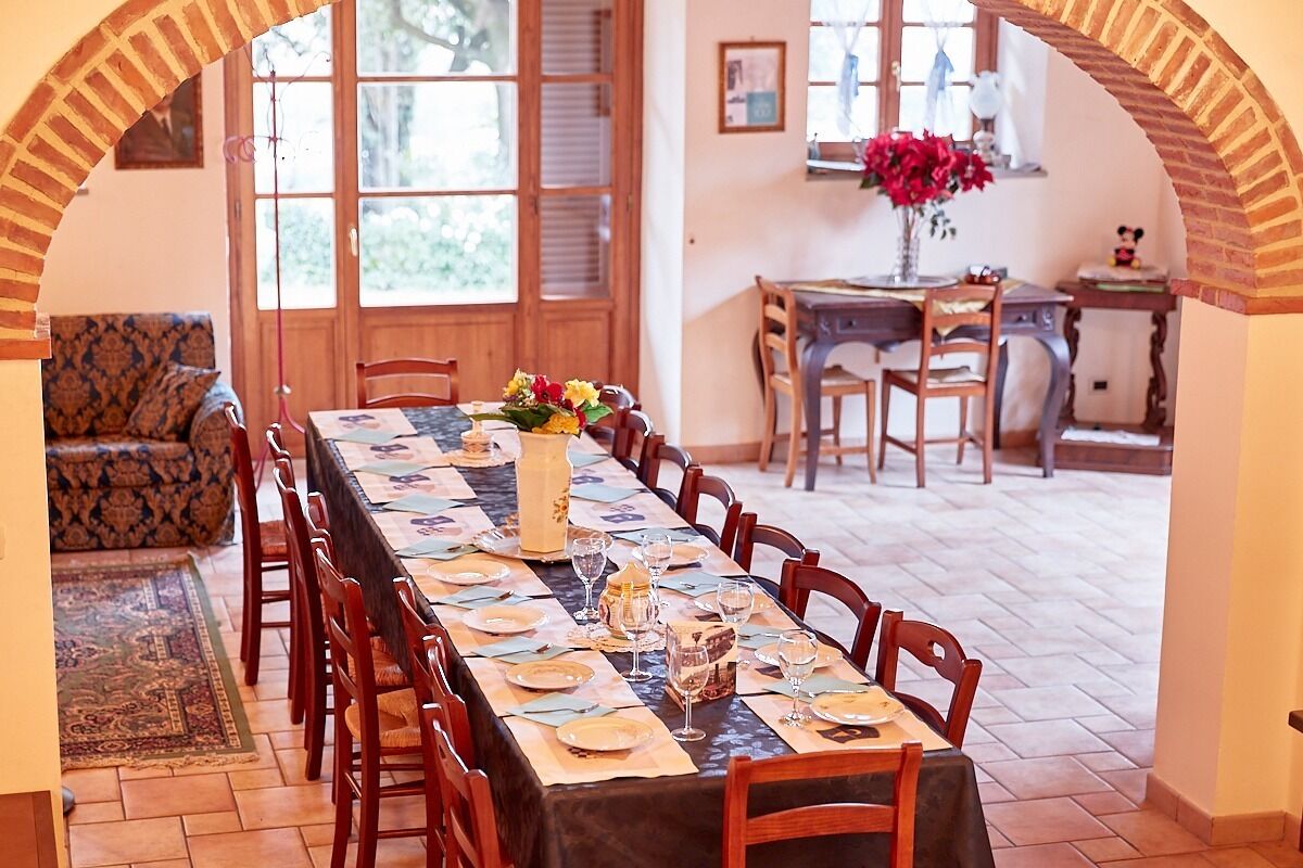 Un espace repas avec une longue table dressée pour le repas, entourée de chaises en bois.