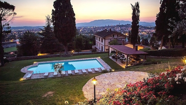 A swimming pool surrounded by a stone deck, a gazebo, and a view of a cityscape at dusk. - Spacious Villa Noble With All the Comfort, Located In A Peaceful Location Arezzo (Arezzo)