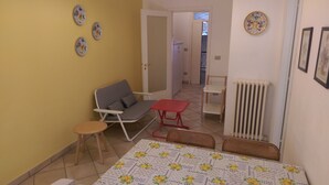 Une petite pièce, de taille modeste, comprenant un canapé, une petite table, un radiateur et une chaise.