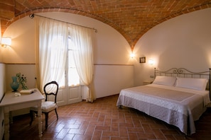 A bedroom with a bed, a chair, a desk, and a window with curtains. - 3BR apartment in agriturismo, ground floor. Shared pool (Cortona)