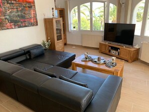 A modern living room with a sectional sofa, a television, and a wooden cabinet.