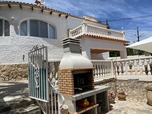 A house with a stone facade, a brick chimney, and a white balcony with balustrades.