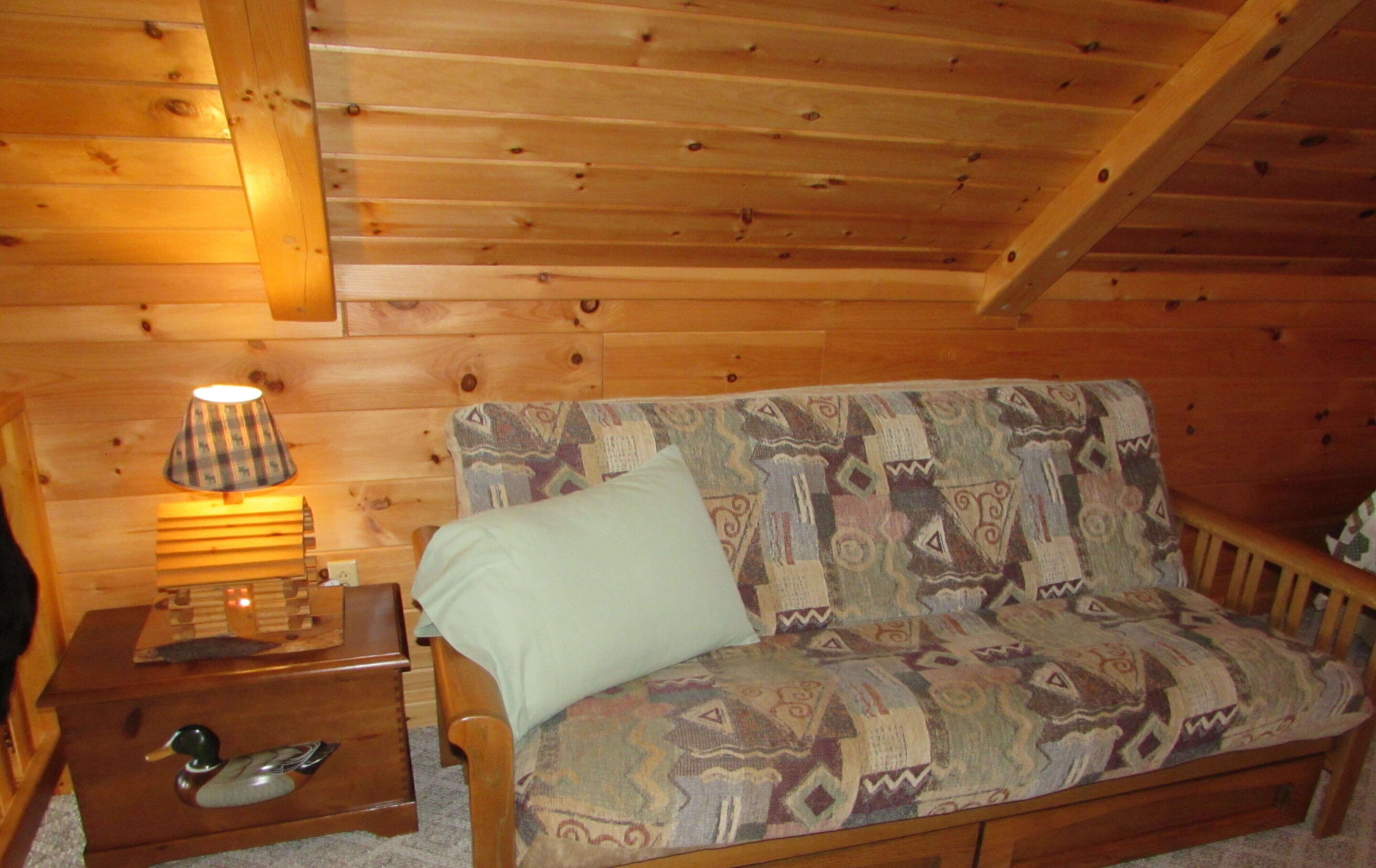 L’intérieur d’un chalet en bois, avec un canapé, une lampe et un tiroir en forme de canard.