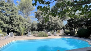 Une piscine avec des chaises longues et un espace aménagé en jardin.