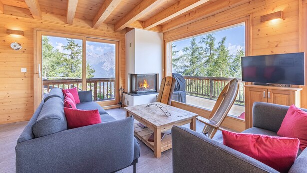 A cozy wooden cabin interior with a sofa, chairs, a table, a fireplace, and a TV. - Ann - SUNNY & LUXE chalet 8 pers (Haute-Nendaz)