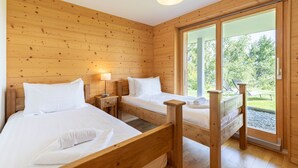 A wooden cabin room with two beds, a nightstand, and a large window. - Ann - SUNNY & LUXE chalet 8 pers (Haute-Nendaz)