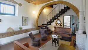 A spacious living area with a high ceiling, a staircase, and a view of the kitchen. - Sughera - Share-croppers house (Impruneta)
