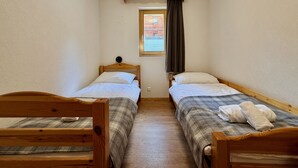 A narrow room with two wooden beds, a window with curtains, and a wooden ceiling beam. - Pracondu 1 107 - OUTDOOR & FUN  charming apartment (Haute-Nendaz)