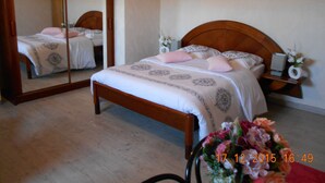 A bedroom with a wooden bed, a nightstand with a lamp, and a mirror. - Bed & Breakfast (Villers-Sur-Port)