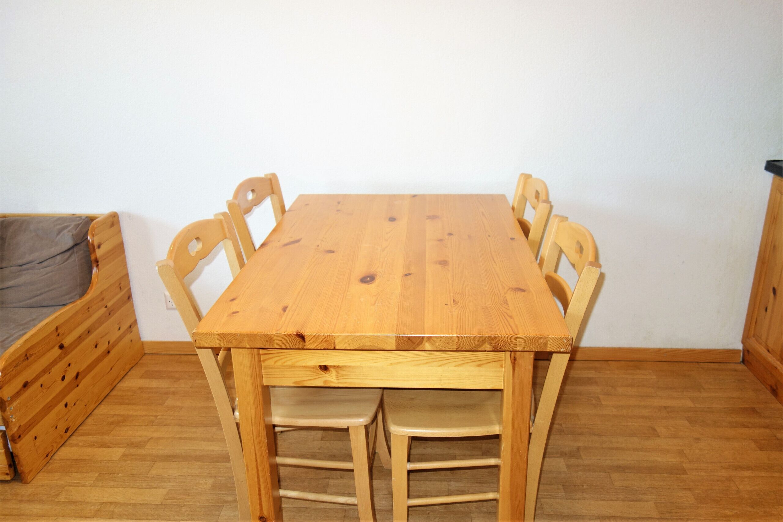 A wooden dining table with four chairs, a bench, and a small wooden cabinet.