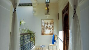 Un couloir avec un sol à motifs, une lanterne suspendue et un tableau accroché au mur.