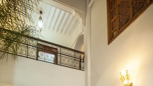 Une cour spacieuse avec une piscine, un coin repas et un balcon agrémenté de balustrades décoratives.