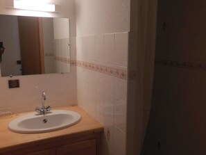 Een badkamer met een wastafel, spiegel en betegelde wanden.