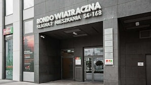 The exterior of a building with a sign reading "Rondo Wiatraczna Klatkatu Mieszkani 54-168".