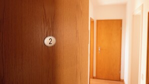 Une porte en bois portant le numéro « 2 », un couloir et une porte fermée au bout.