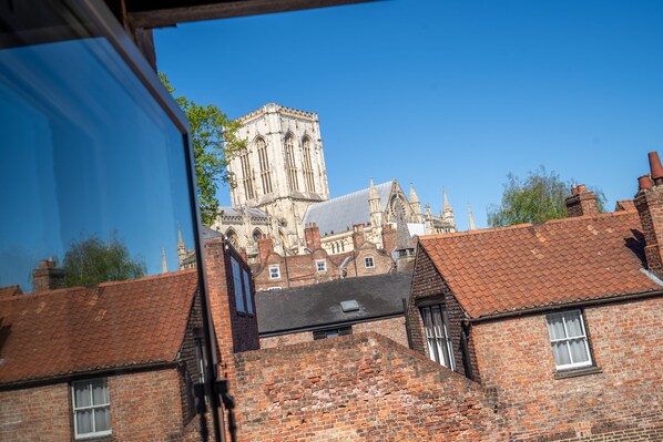 A historic building with a prominent tower, adjacent brick buildings, and a clear blue sky.