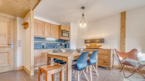 Une cuisine moderne avec des meubles en bois, une table à manger avec des chaises et un luminaire suspendu.