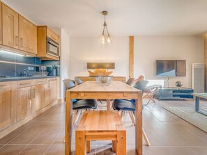Una cocina moderna con armarios de madera, una isla central y un comedor con mesa y sillas de madera.