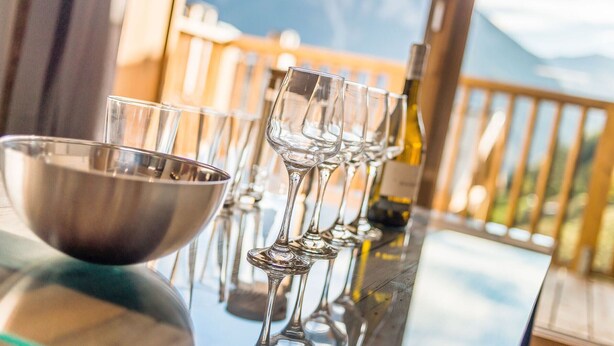 Un espace bar offrant une vue sur les montagnes, un saladier en métal et des verres à vin.