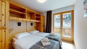 Une pièce en bois avec deux lits, un balcon et une grande fenêtre.