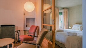 Una habitación con cama, una silla, una mesa y una ventana con cortinas.