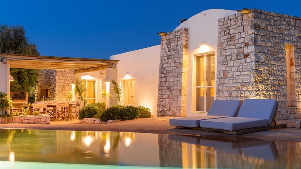 A poolside area with a stone building, lounge chairs, and a covered seating area. - Luxury villa for 6 people with salt pool and in the middle of 14,000sqm  (Ostuni)