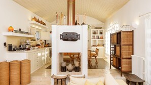A modern kitchen with white cabinets, a central stove, and a dining area with wooden furniture. - Luxury villa for 6 people with salt pool and in the middle of 14,000sqm  (Ostuni)