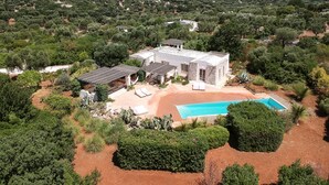 A large house with a swimming pool, surrounded by dense greenery and a clear sky. - Luxury villa for 6 people with salt pool and in the middle of 14,000sqm  (Ostuni)