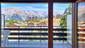 Ein Balkon mit Blick auf Berge, Holzhäuser und einem Stuhl.