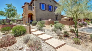 A two-story house with a stucco exterior, a balcony, and a paved driveway leading to the entrance.