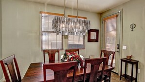 A dining room with a wooden table and chairs, a chandelier, and a vase of flowers.