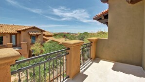 A balcony with a view of neighboring houses and a clear sky.