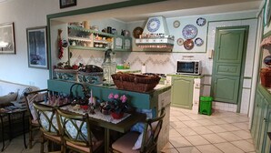 A cozy kitchen with a dining area, featuring a green cabinet, a microwave, and various kitchen utensils. - Cyclope's House.  Amazing view and private mini SPA. (Vampolieri I)