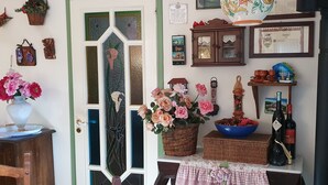 A room with a decorative door, a vase of flowers, a wicker basket, a wine bottle, and a framed certificate on the wall. - Cyclope's House.  Amazing view and private mini SPA. (Vampolieri I)