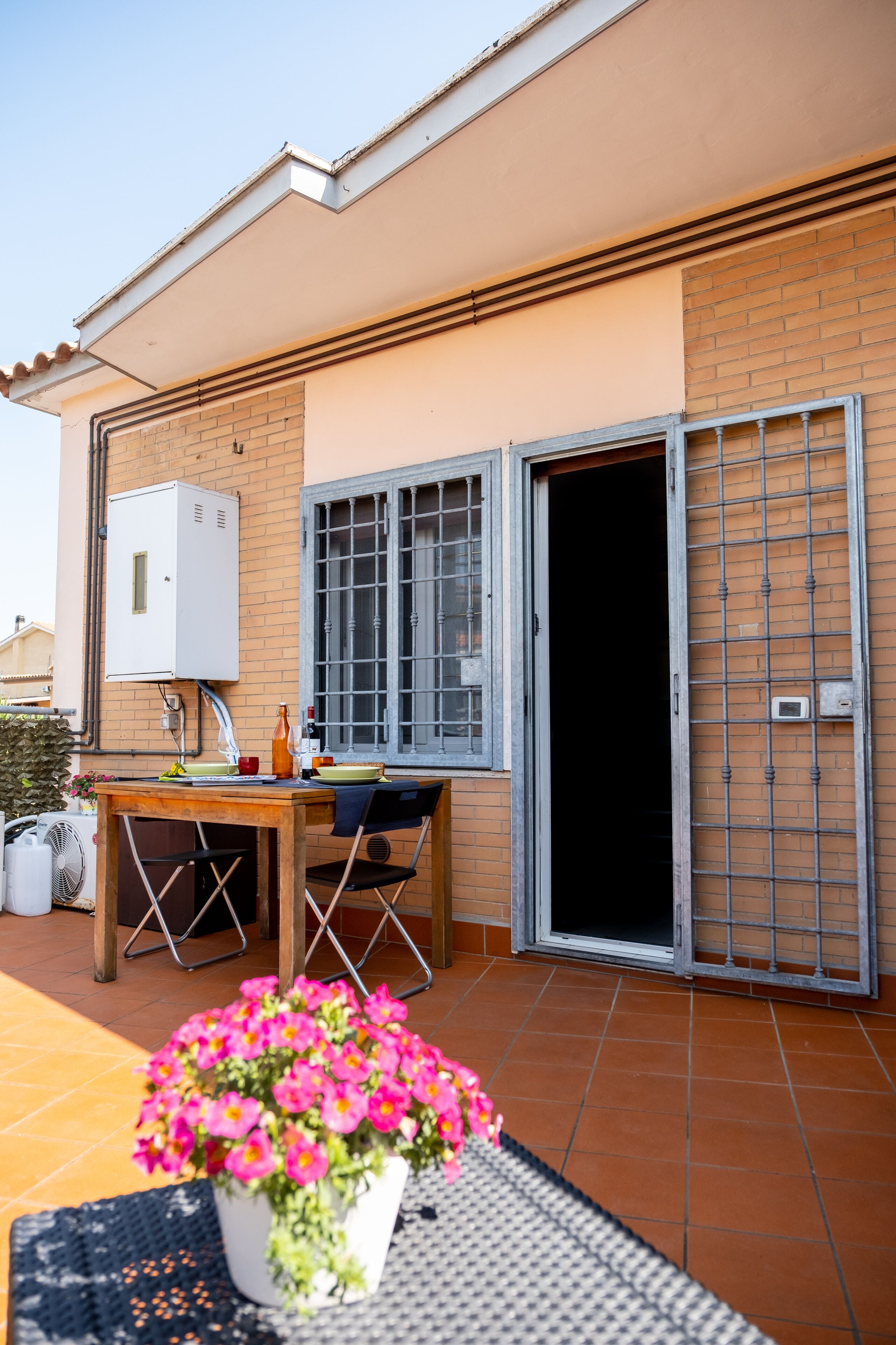 A patio with a table, chairs, a potted plant, and a sliding door.