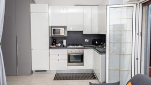 A modern kitchen with white cabinets, a microwave, stove, and oven. - FIUMICINO BUSINESS & VACATION APARTMENT CIR 5572 (Fiumicino)
