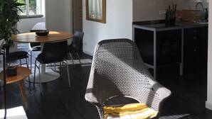 Una cocina moderna con armarios oscuros, un comedor con una mesa redonda y sillas, un espejo grande y un televisor sobre la encimera.