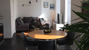 Una sala de estar moderna con una mesa redonda de comedor, sillas negras, un sofá y una lámpara colgante grande.