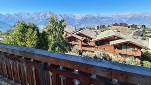 A mountain lodge with wooden cabins, a wooden deck, and a view of snow-capped mountains in the background.