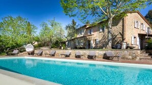 Un bâtiment en pierre doté d’une piscine et de chaises longues.