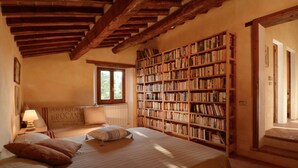 Une chambre avec une grande bibliothèque en bois, un lit avec une literie à rayures et une fenêtre donnant sur l’extérieur.