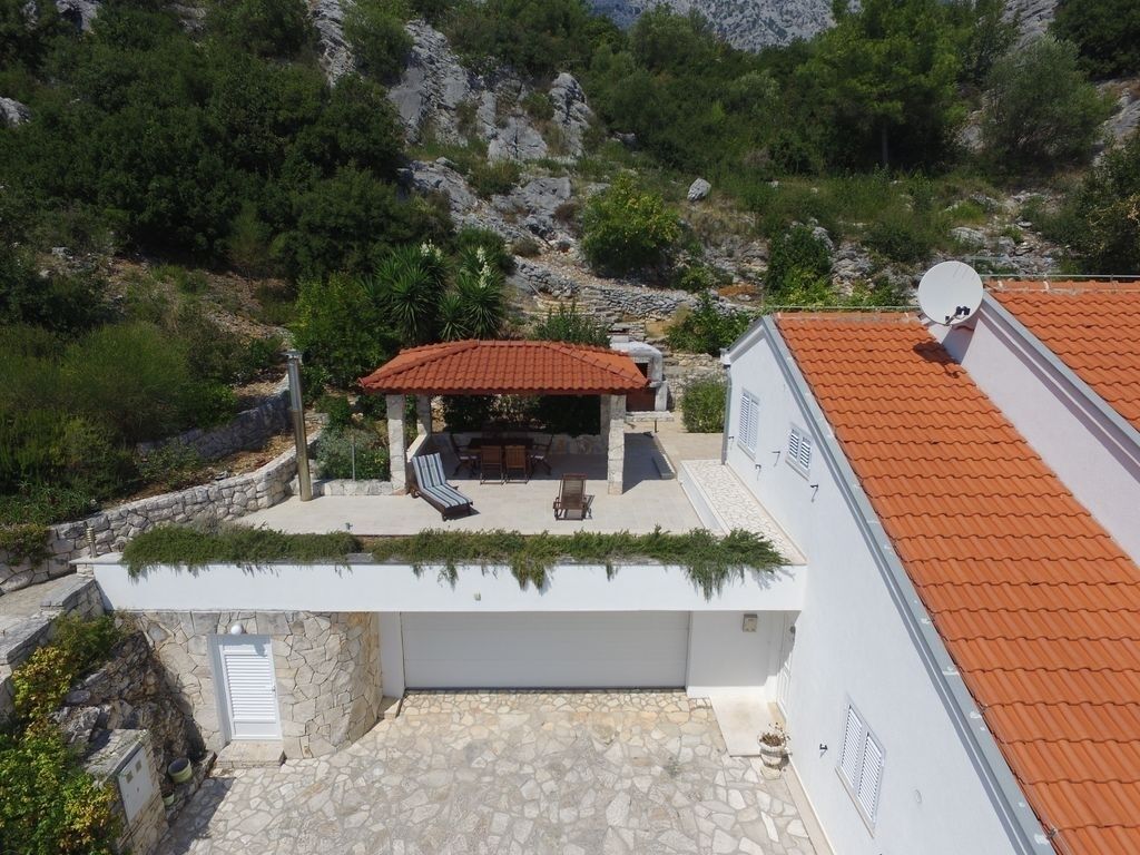 Un edificio moderno con un patio de piedra, una zona de estar cubierta al aire libre y una antena parabólica.
