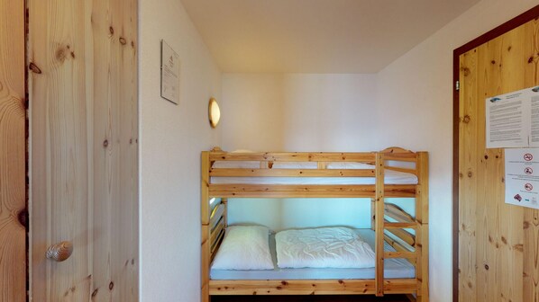 A bunk bed room with wooden walls and a door.