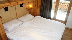 A wooden room with a bed, a nightstand, and a window with a view of a wooden deck. - Pracondu 1 306 - OUTDOOR & FUN  charming apartment (Haute-Nendaz)