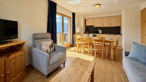 A modern living room with a sofa, a television, a dining table with chairs, and a kitchen area. - Pracondu 1 405 - OUTDOOR & FUN  apartment 6 pers (Haute-Nendaz)