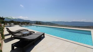 Piscina con sillones de descanso y vista a las montañas.