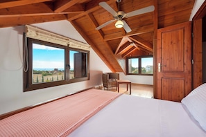 A bedroom with a bed, a chair, a wooden door, and a window with a view.