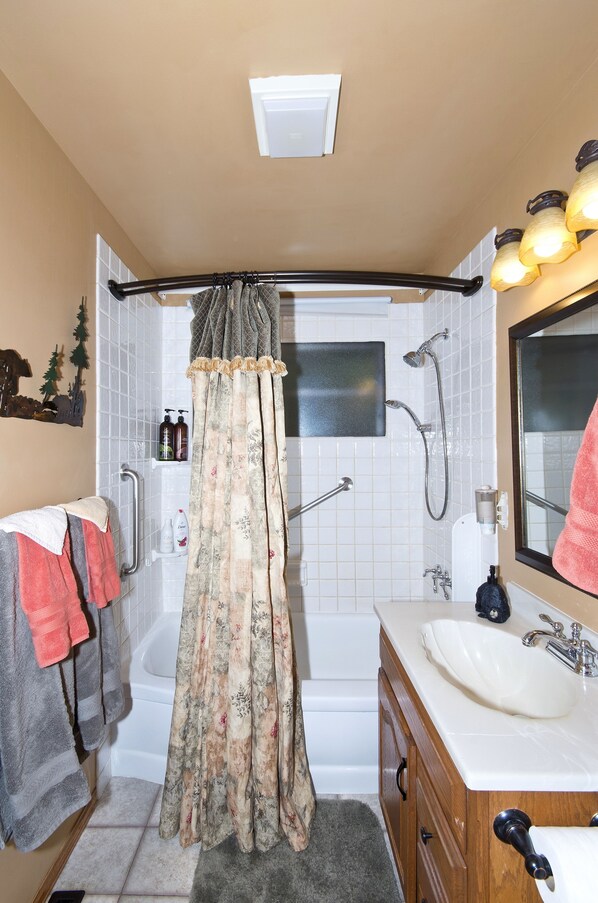 Une salle de bain avec une baignoire, une douche, un lavabo et un miroir.