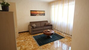 A living room with a sofa, a coffee table, and a painting on the wall. - Miramare 2 appartamento trilocale in complesso residenziale (TAGGIA)