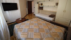 A room with a bed, a TV, a sofa, and a wardrobe. - Miramare 2 appartamento trilocale in complesso residenziale (TAGGIA)